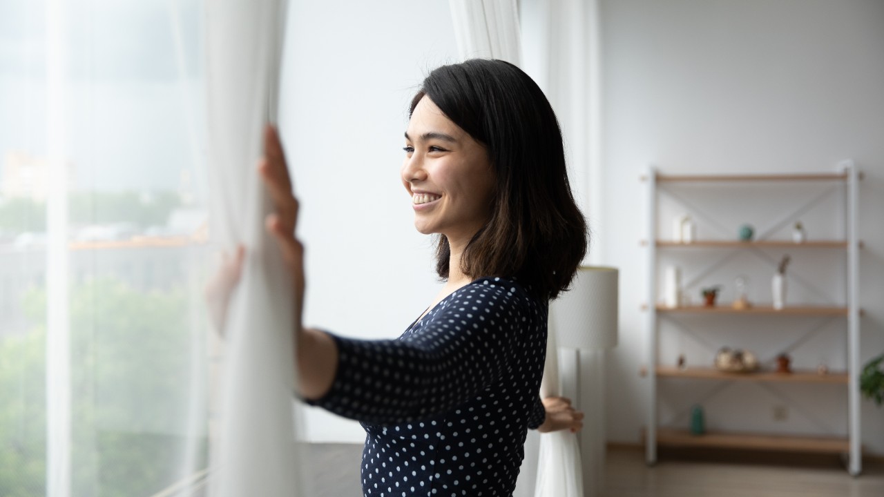 A woman with a big smile on her face looking out the window to make a positive change in the world