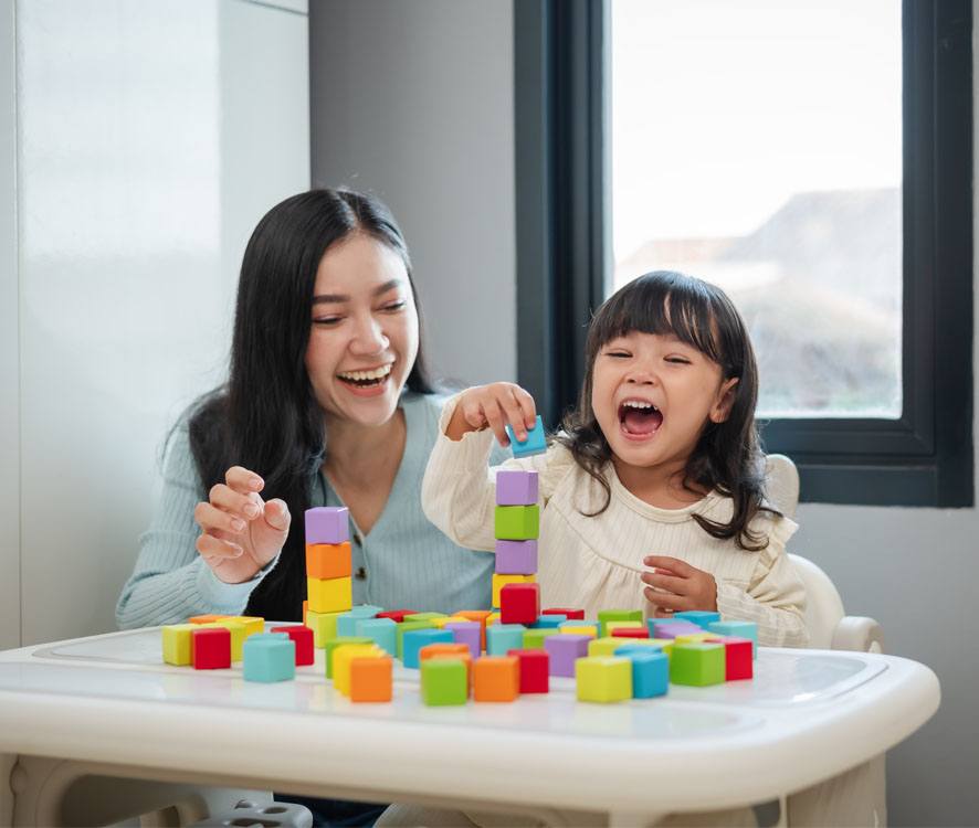 mother and daughter playing with blocks on a table